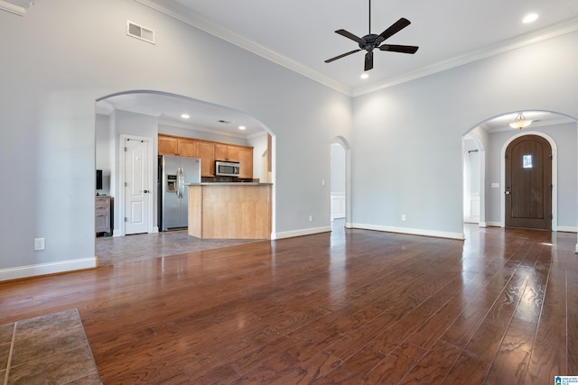 unfurnished living room with a high ceiling, dark hardwood / wood-style floors, ceiling fan, and ornamental molding