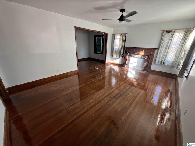 unfurnished living room with a fireplace, a wealth of natural light, dark hardwood / wood-style flooring, and ceiling fan