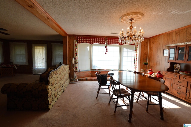 carpeted dining area with beamed ceiling, wood walls, a textured ceiling, and an inviting chandelier