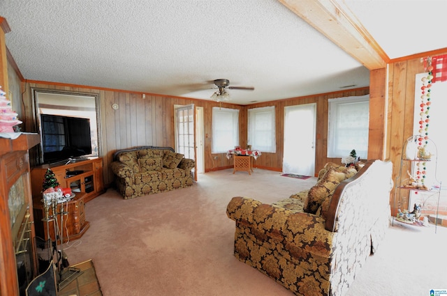 carpeted living room featuring a textured ceiling, ceiling fan, and wood walls