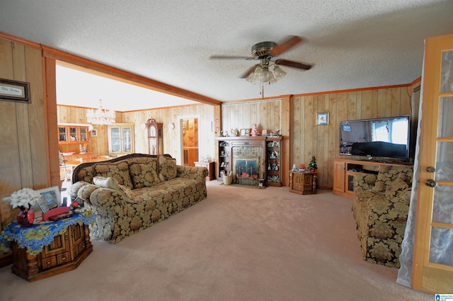 living room with wooden walls, carpet, ceiling fan with notable chandelier, and a textured ceiling