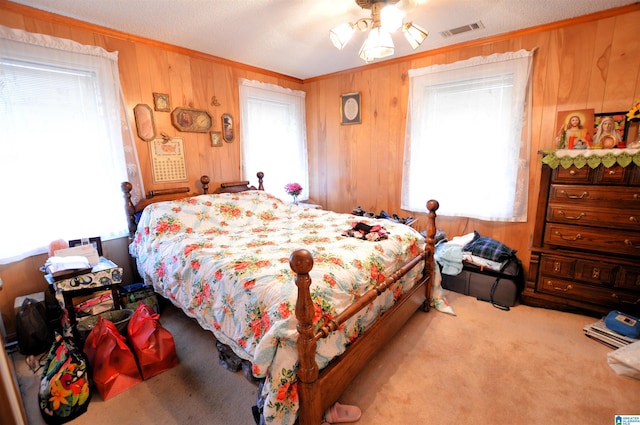 carpeted bedroom featuring multiple windows, ceiling fan, and wood walls