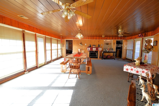 dining space with ceiling fan, wood walls, and wooden ceiling