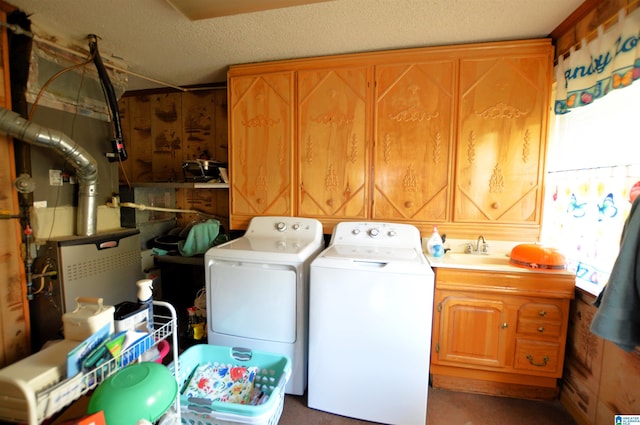 clothes washing area featuring cabinets, a textured ceiling, washing machine and dryer, and sink