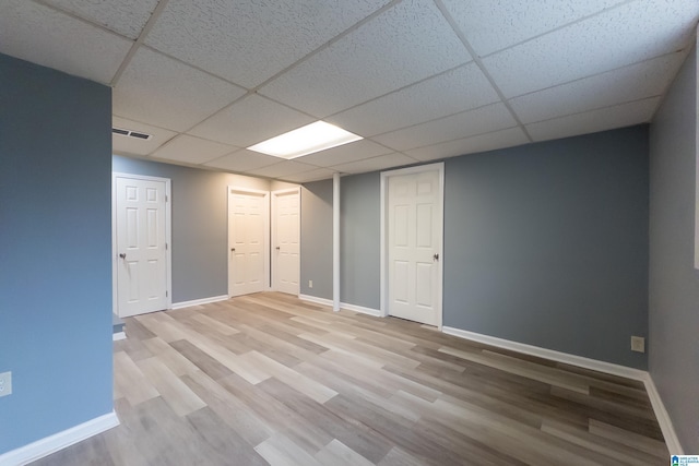 basement with a paneled ceiling and hardwood / wood-style flooring