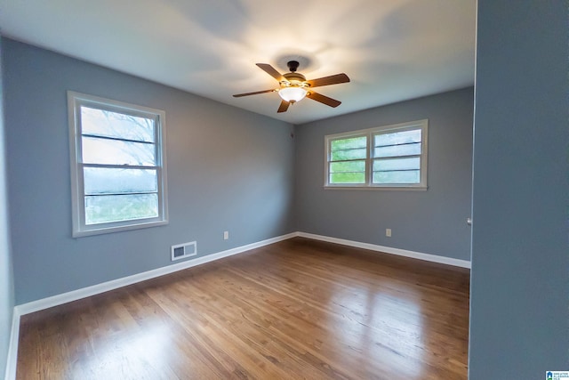 spare room with ceiling fan, hardwood / wood-style floors, and a healthy amount of sunlight