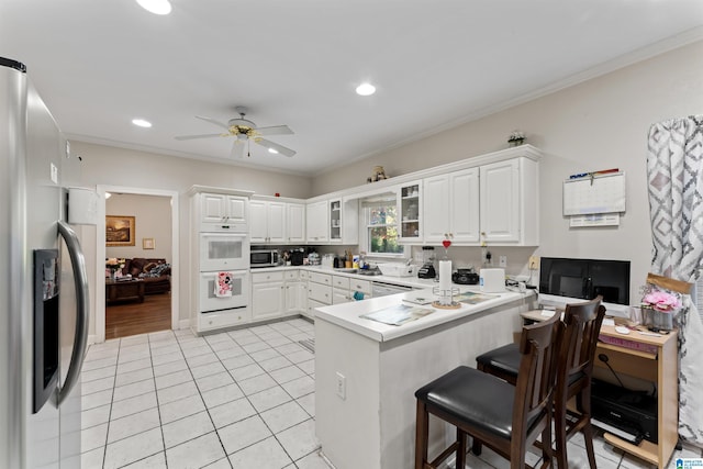 kitchen with white cabinetry, kitchen peninsula, a breakfast bar area, and appliances with stainless steel finishes