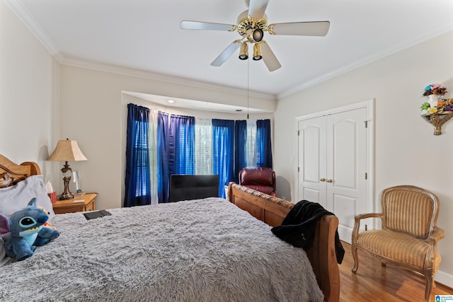 bedroom with hardwood / wood-style floors, a closet, ceiling fan, and crown molding