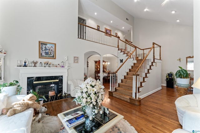 living room with a premium fireplace, hardwood / wood-style floors, a high ceiling, and an inviting chandelier