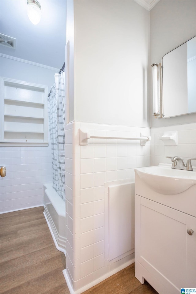 bathroom featuring ornamental molding, hardwood / wood-style flooring, tile walls, and shower / bath combo with shower curtain