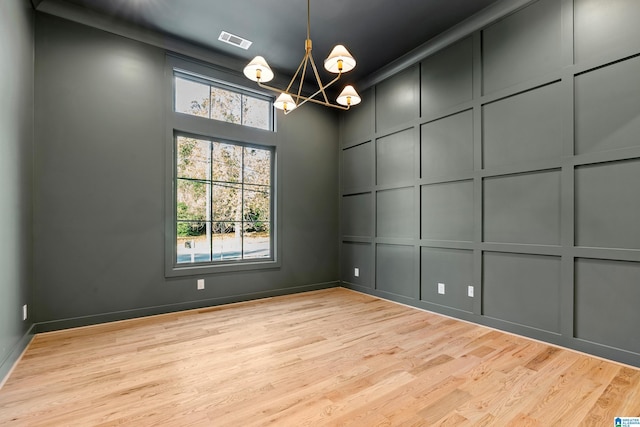 empty room with an inviting chandelier and light hardwood / wood-style flooring