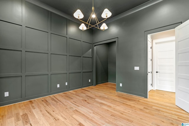 empty room with an inviting chandelier and light hardwood / wood-style flooring