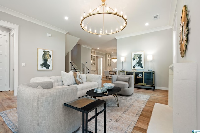 living room featuring a chandelier, crown molding, and light hardwood / wood-style flooring