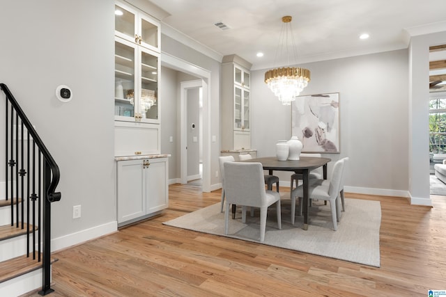 dining space with light hardwood / wood-style floors, a notable chandelier, and ornamental molding