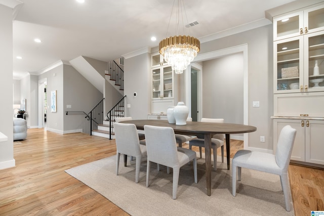 dining room featuring light wood-type flooring, crown molding, and an inviting chandelier