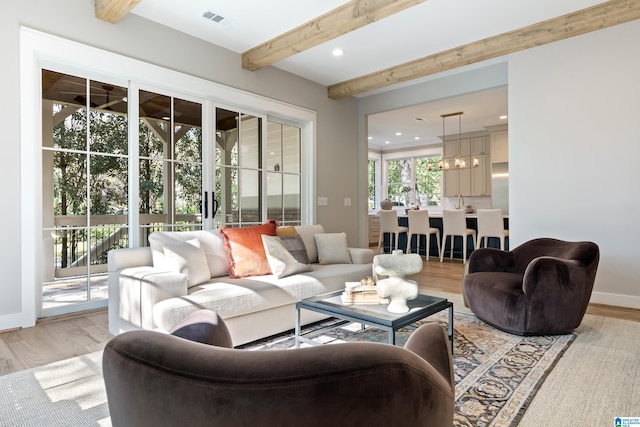 living room featuring beam ceiling, light hardwood / wood-style floors, and a chandelier