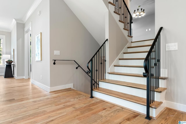 staircase featuring hardwood / wood-style floors, a notable chandelier, and ornamental molding