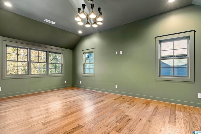 unfurnished room featuring light hardwood / wood-style floors, vaulted ceiling, a healthy amount of sunlight, and a notable chandelier