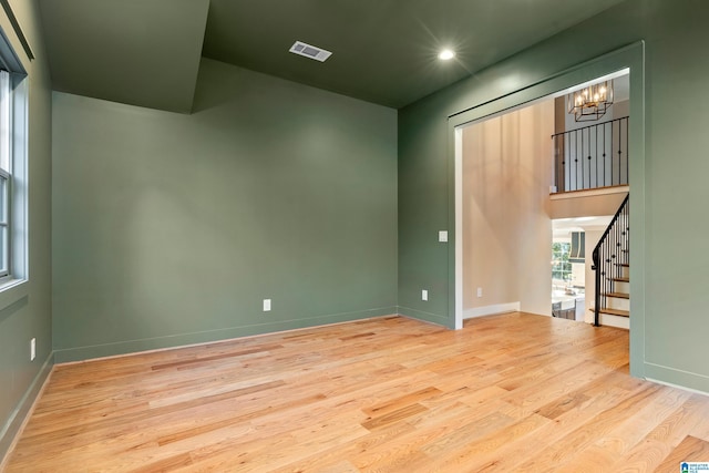 spare room featuring light hardwood / wood-style floors and a chandelier