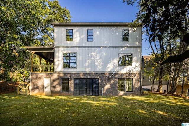 rear view of house featuring ceiling fan and a yard