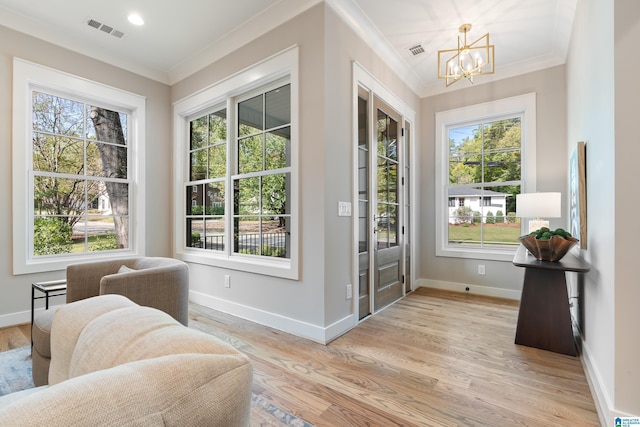 doorway to outside with a wealth of natural light, a chandelier, and light wood-type flooring