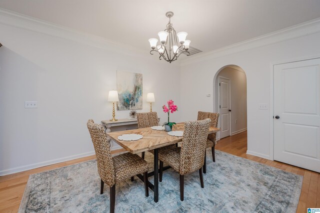 dining space with a notable chandelier, light hardwood / wood-style floors, and crown molding