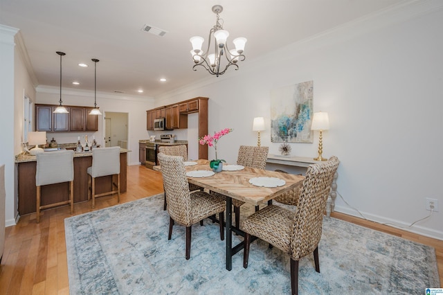 dining room with ornamental molding, light hardwood / wood-style flooring, and a notable chandelier