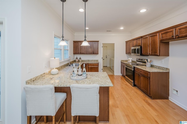 kitchen with kitchen peninsula, appliances with stainless steel finishes, light wood-type flooring, sink, and decorative light fixtures