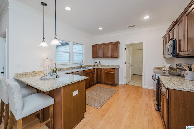 kitchen with pendant lighting, light hardwood / wood-style flooring, light stone countertops, kitchen peninsula, and stainless steel appliances