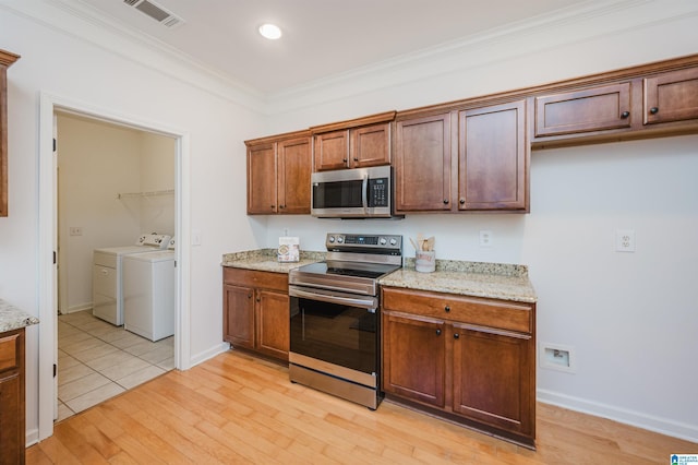 kitchen with light wood-type flooring, light stone counters, ornamental molding, stainless steel appliances, and washing machine and dryer