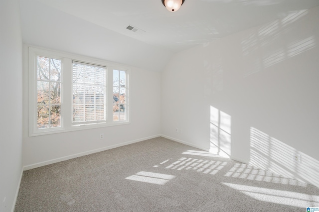 carpeted spare room with vaulted ceiling