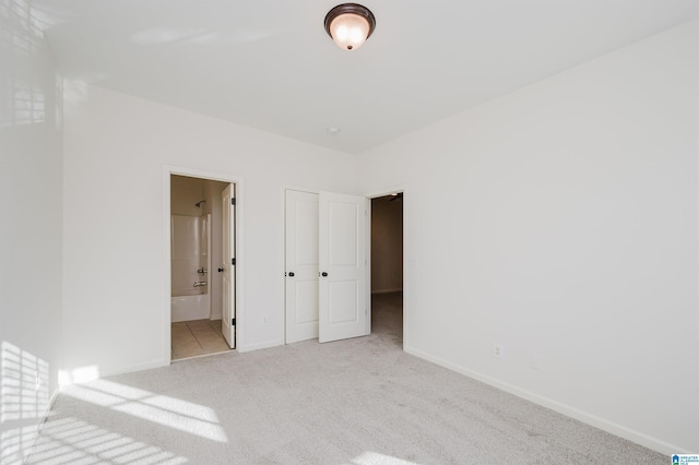 unfurnished bedroom featuring light carpet and ensuite bath