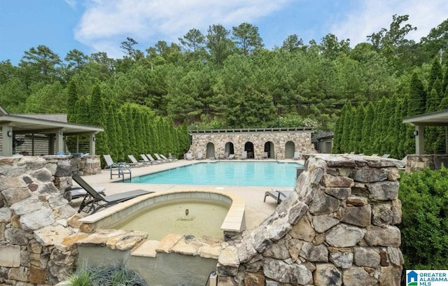 view of swimming pool with a hot tub and a patio area