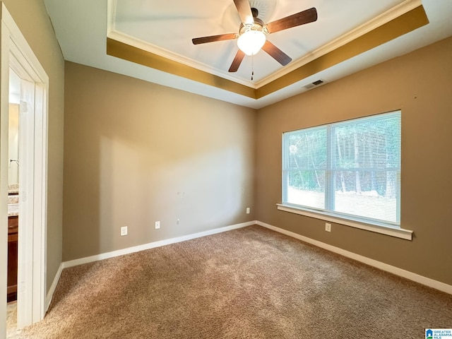 carpeted spare room featuring ceiling fan, a raised ceiling, and crown molding