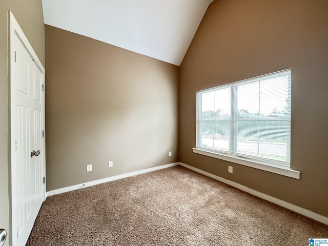 carpeted empty room with vaulted ceiling