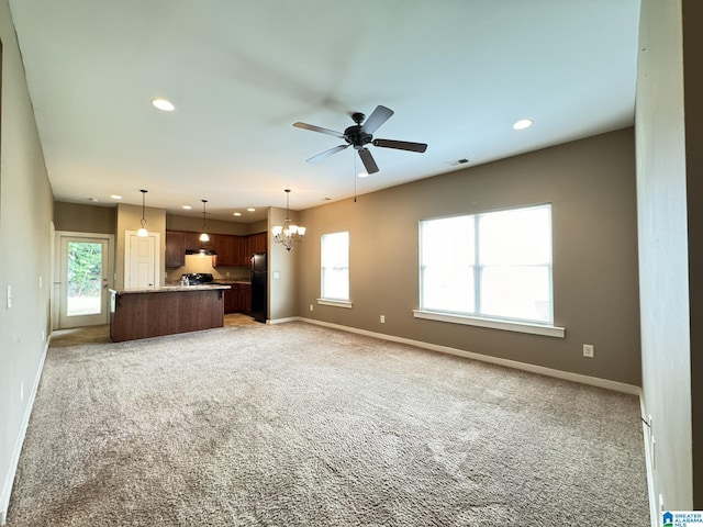 unfurnished living room featuring ceiling fan with notable chandelier and light carpet