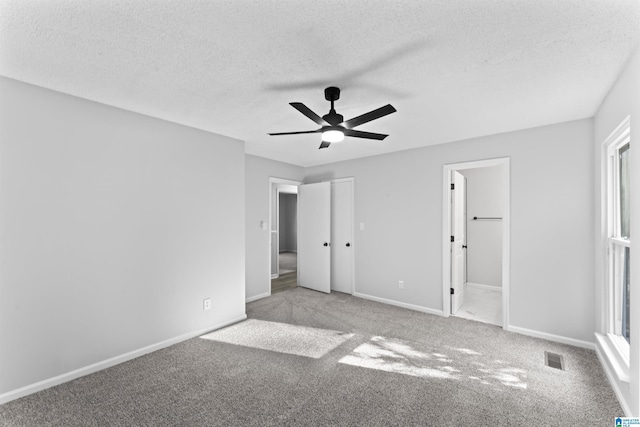 unfurnished bedroom with multiple windows, a textured ceiling, carpet floors, and ceiling fan