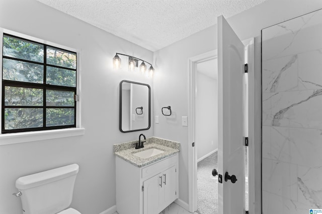 bathroom featuring vanity, toilet, tiled shower, and a textured ceiling