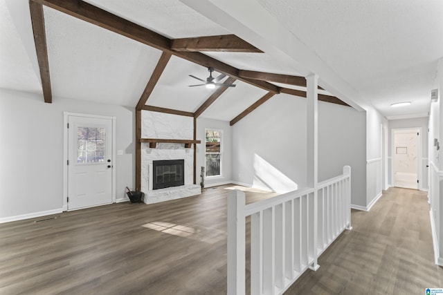 unfurnished living room with vaulted ceiling with beams, dark hardwood / wood-style flooring, a healthy amount of sunlight, and a fireplace