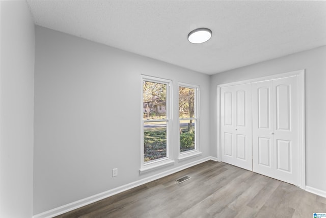 unfurnished bedroom featuring a closet, a textured ceiling, and light hardwood / wood-style flooring