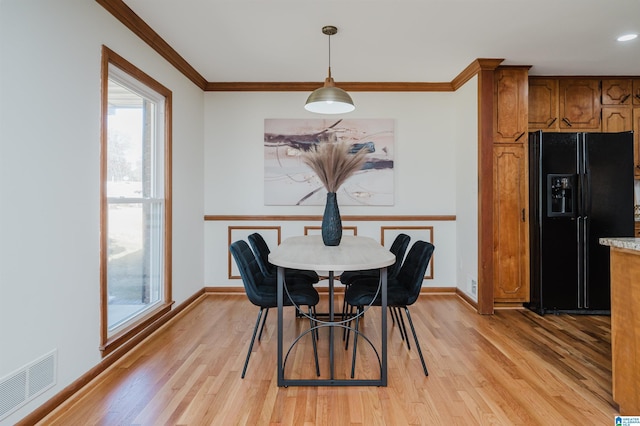 dining area featuring crown molding and light wood-type flooring