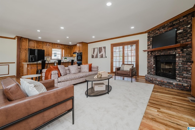 living room featuring a fireplace, light hardwood / wood-style flooring, and crown molding