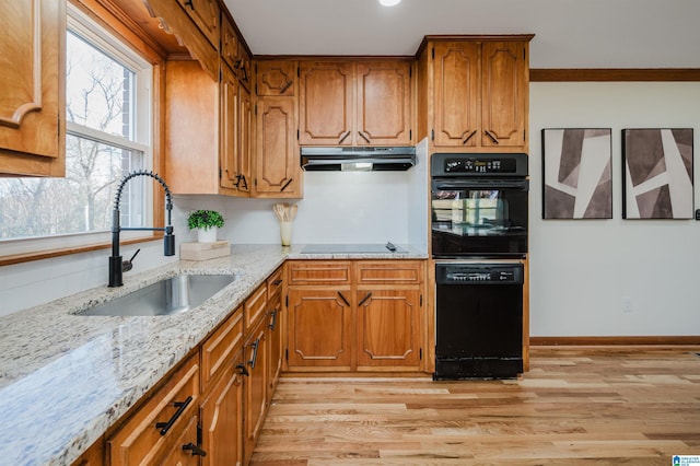 kitchen with backsplash, light stone counters, sink, black appliances, and light hardwood / wood-style flooring