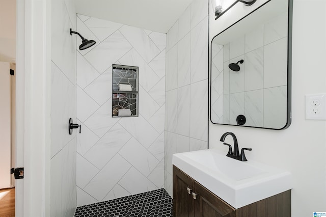 bathroom with tiled shower and vanity