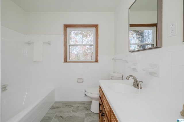 bathroom with vanity, a healthy amount of sunlight, toilet, and tile walls