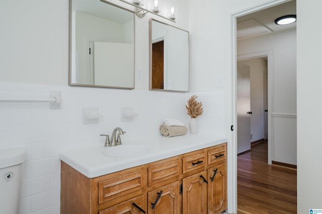 bathroom featuring vanity, toilet, wood-type flooring, and tile walls