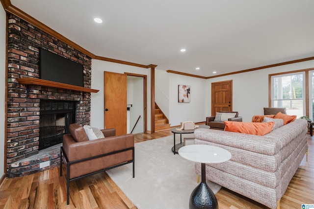 living room with a fireplace, crown molding, and light hardwood / wood-style flooring