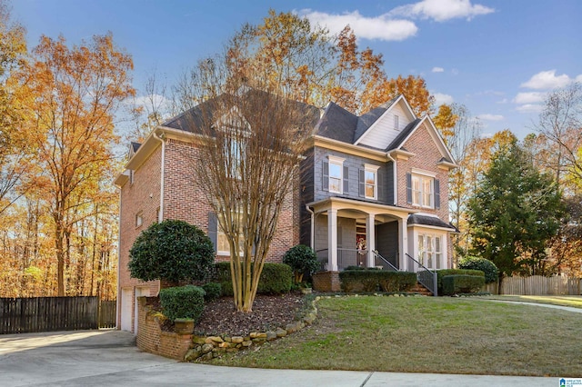 front of property with covered porch, a garage, and a front yard