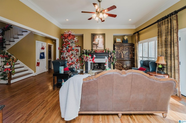 living room with hardwood / wood-style flooring, ceiling fan, and ornamental molding