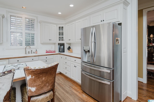 kitchen with white cabinets, stainless steel refrigerator with ice dispenser, and light wood-type flooring